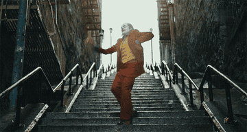 Joaquin Phoenix dancing as the joker on some stairs outside