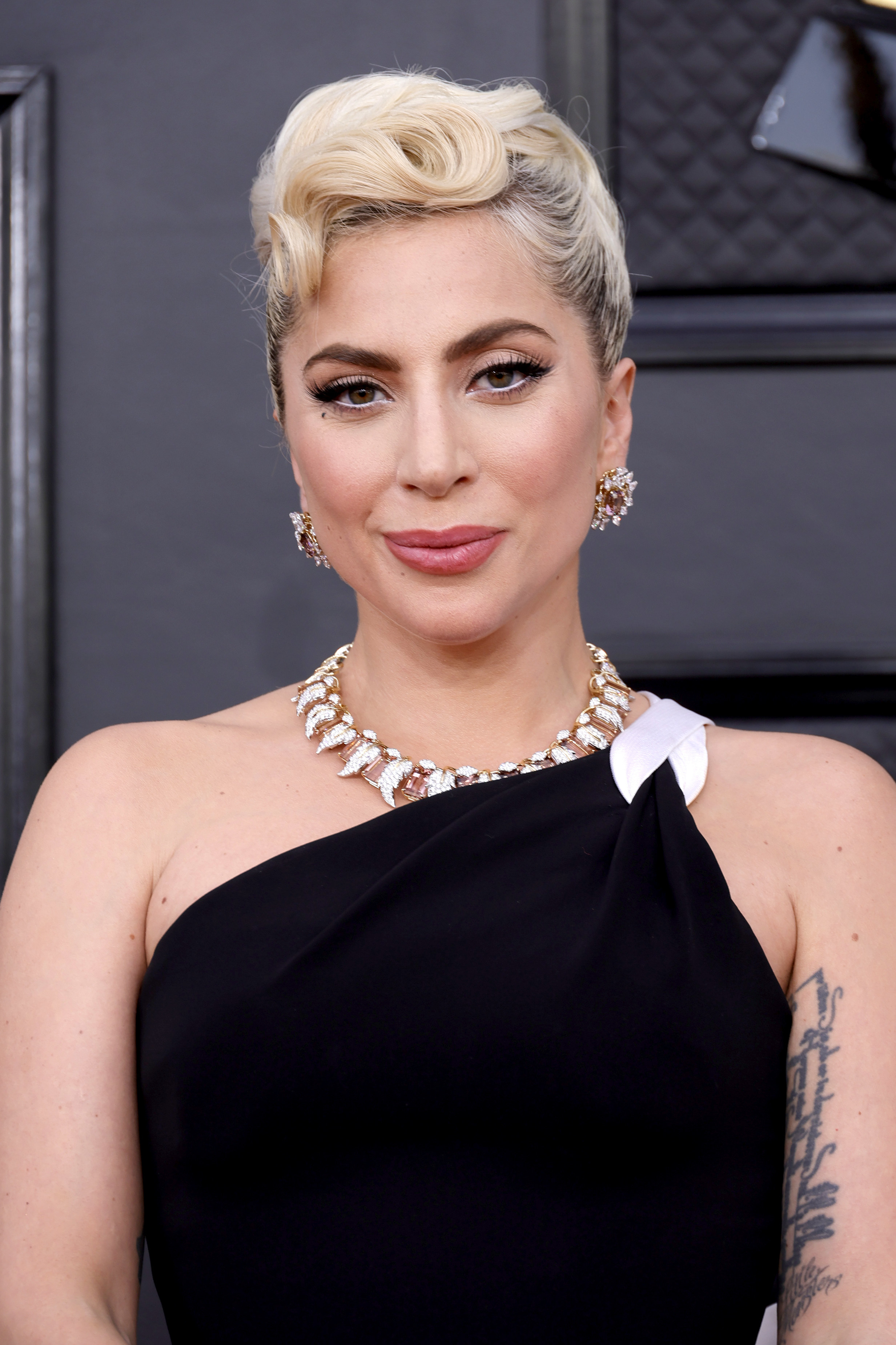 A closeup of Gaga rocking a one-shouldered outfit on the red carpet and her hair in a glam updo