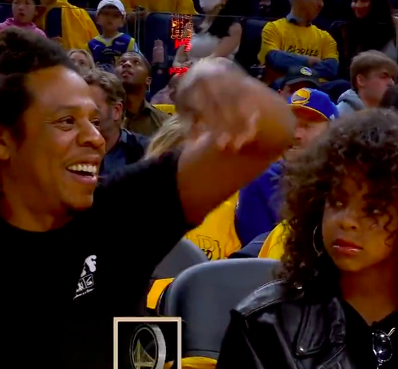 Jay-Z smiling wildly while Blue Ivy stares at him with a blank expression