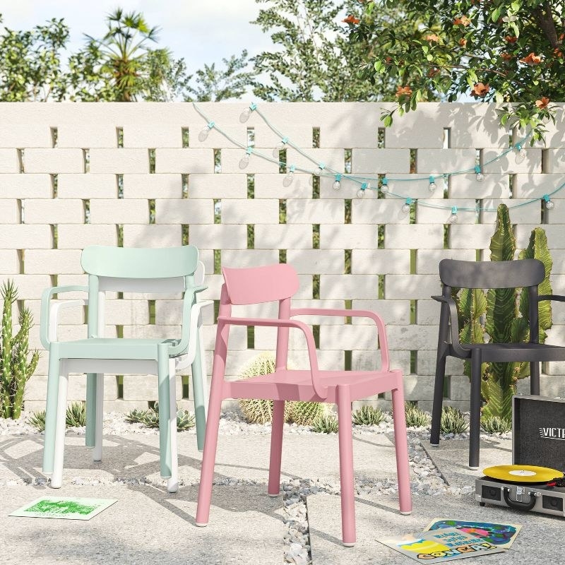 Mint, pink, and black-colored chairs on back patio; a stone wall, plants, and a mini record player are nearby