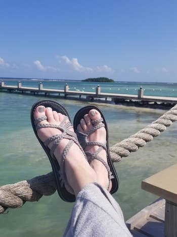 reviewer wearing same sandals in a gray color