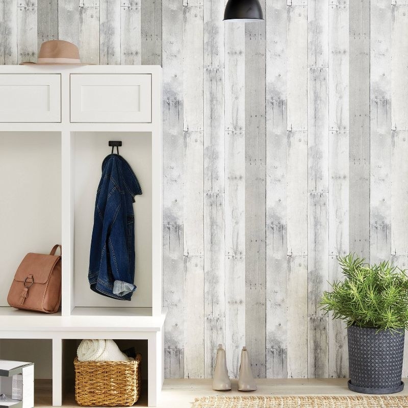 Wallpaper in entryway with storage shelving, boots, and a potted plant