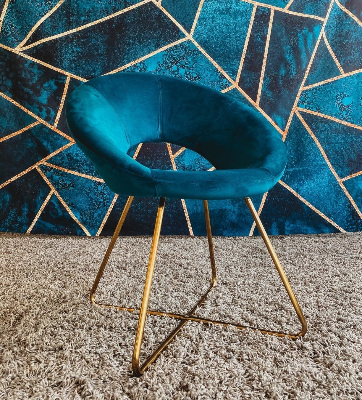 reviewer photo of the blue and gold velvet chair in front of a wall with a matching color scheme