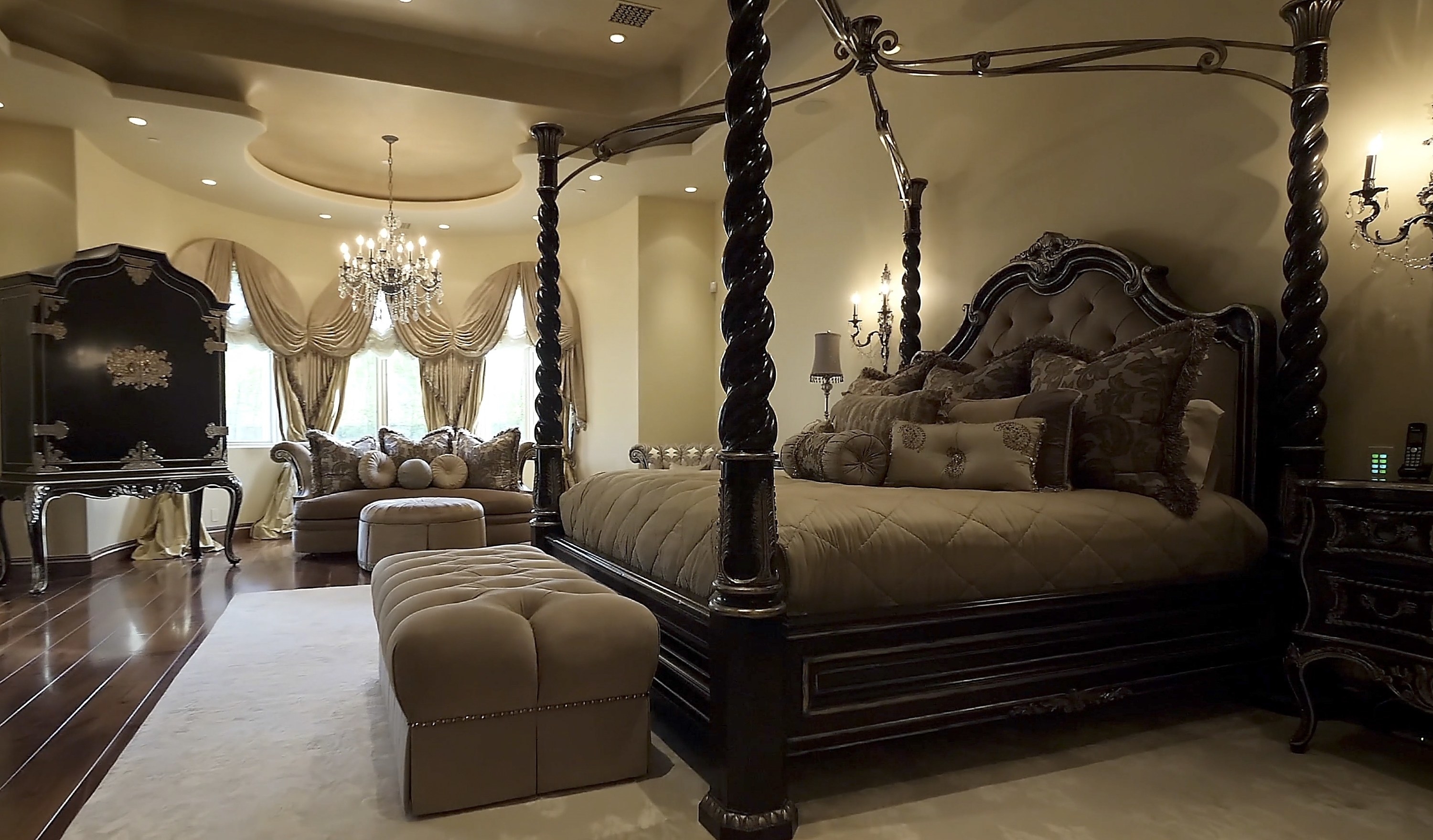 The same bedroom with lots of pillows from before but from a different angle, where you can see a large chandelier hanging over the couch