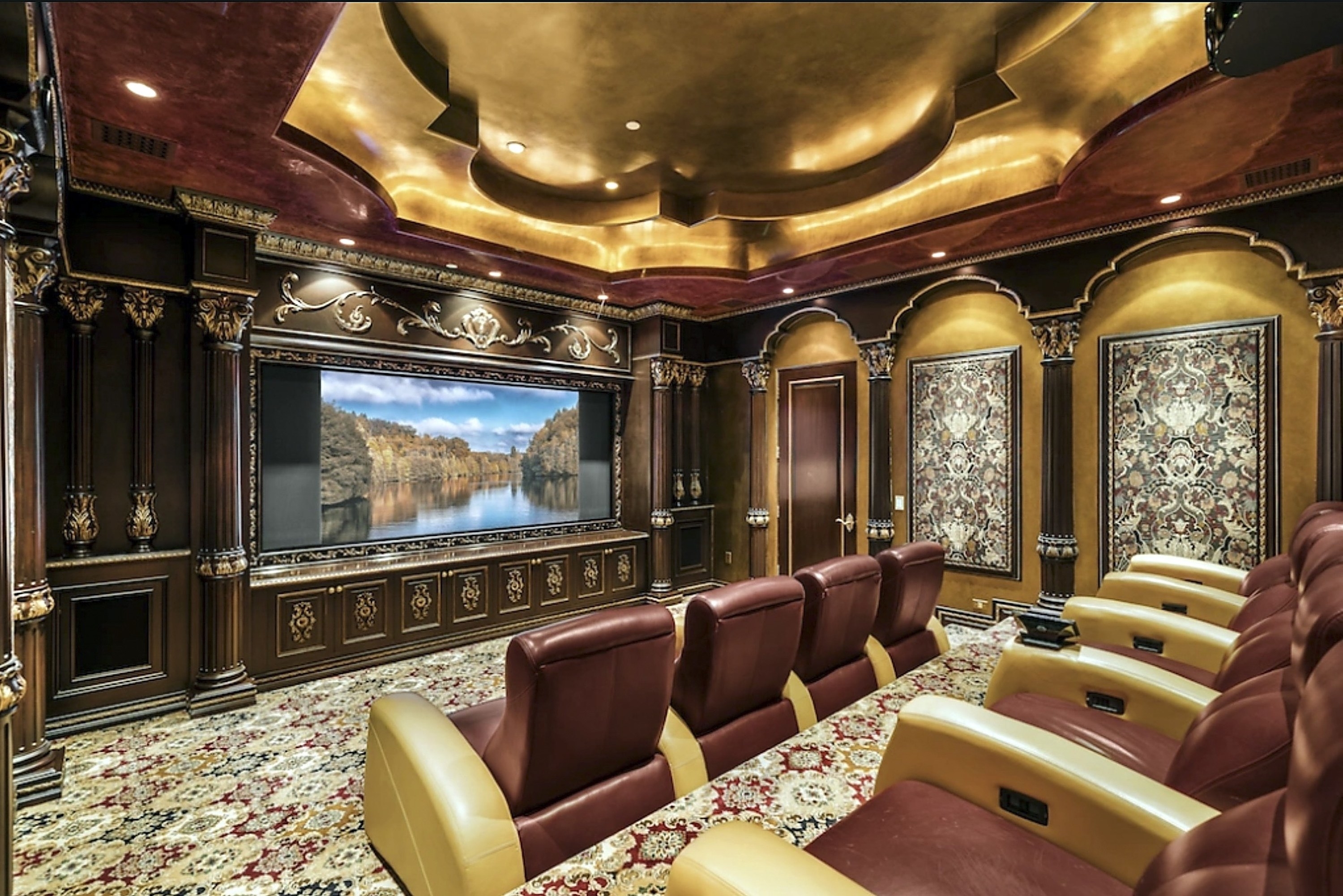 A personal movie theater that has a large TV with several reclining chairs set up in raised tiers