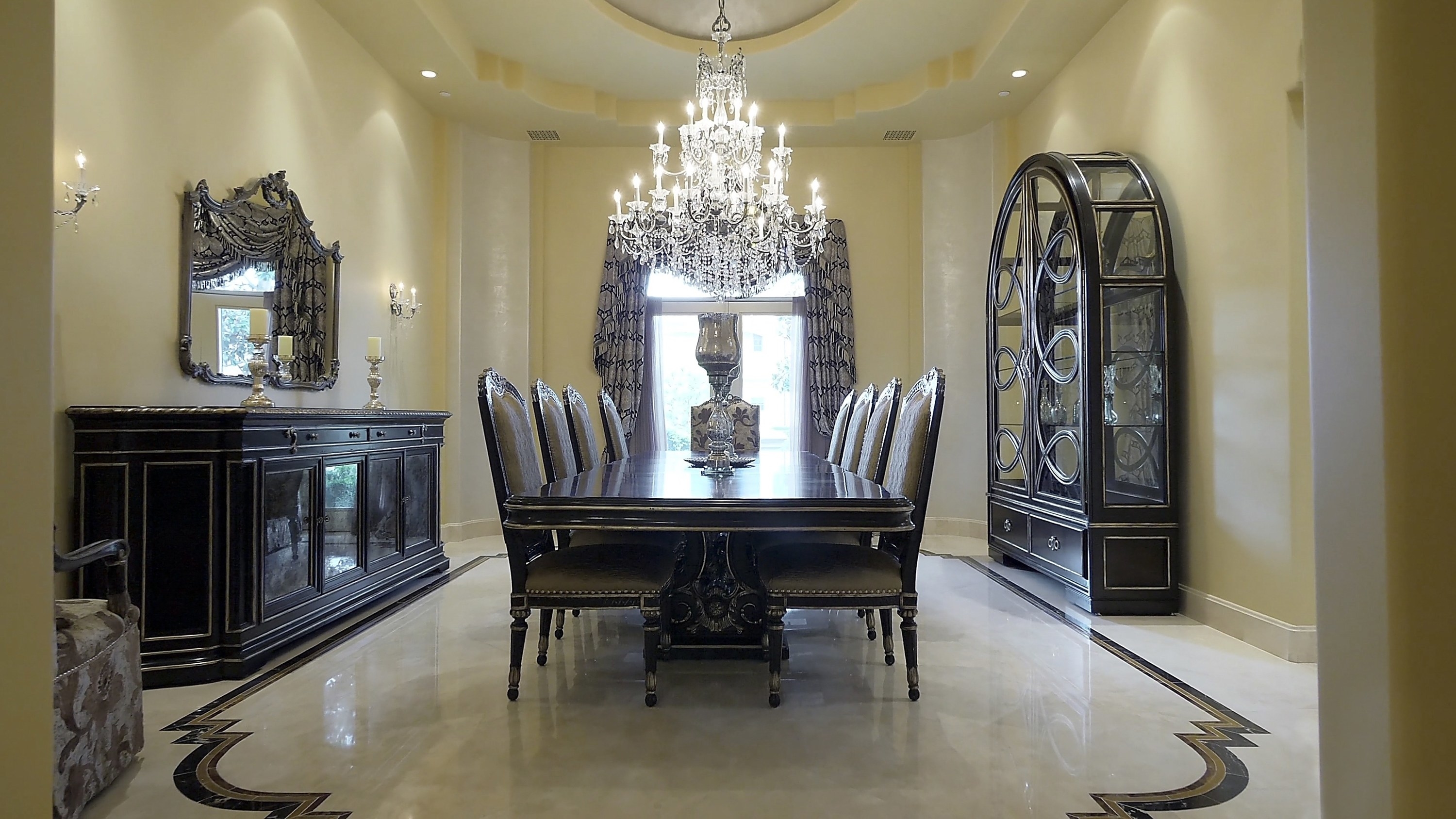 The dining room has an ornate chandelier and shiny marble floors