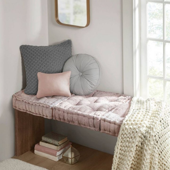 the square pillow on a bench in pink