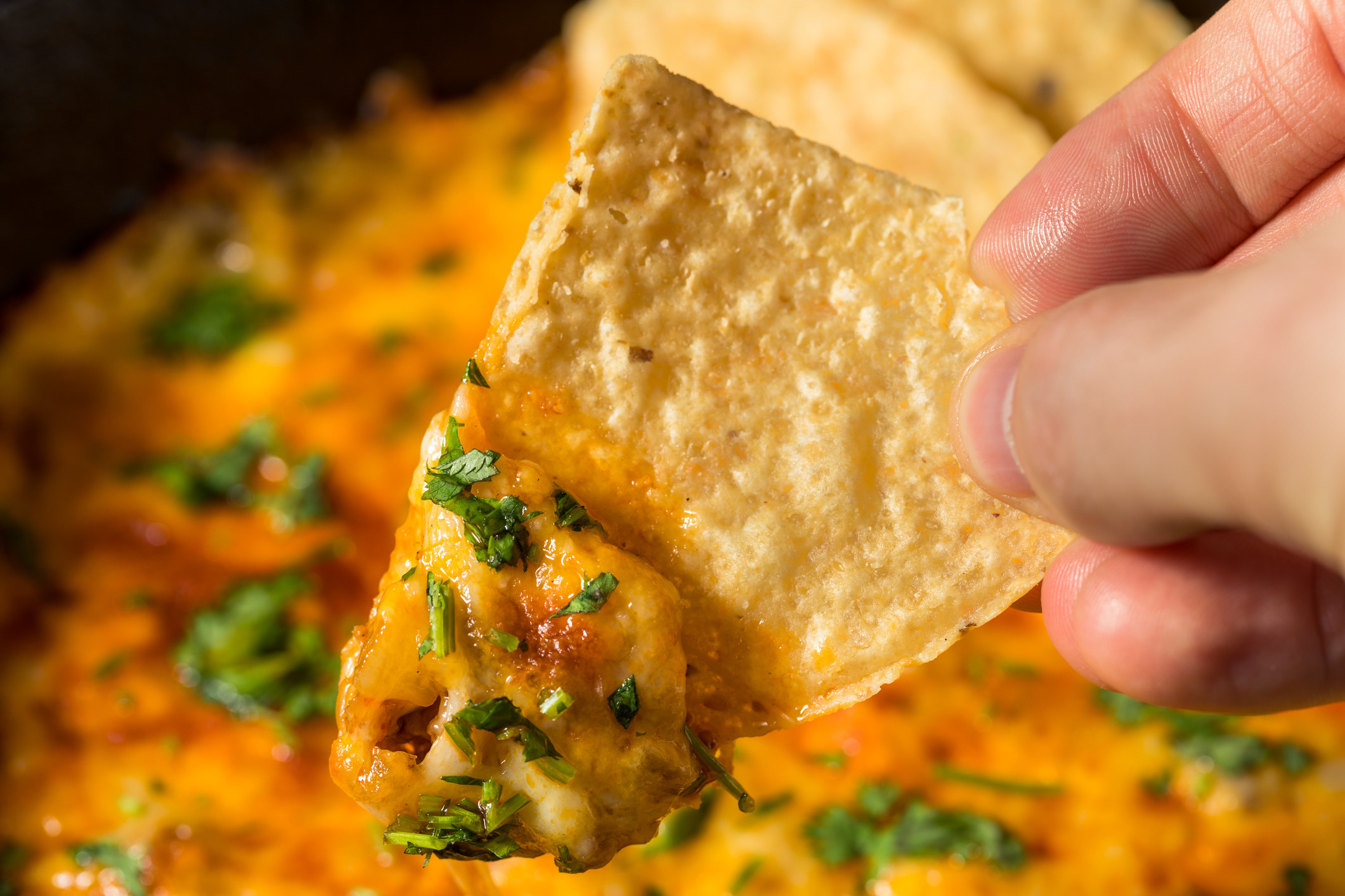 Dipping a chip into queso.