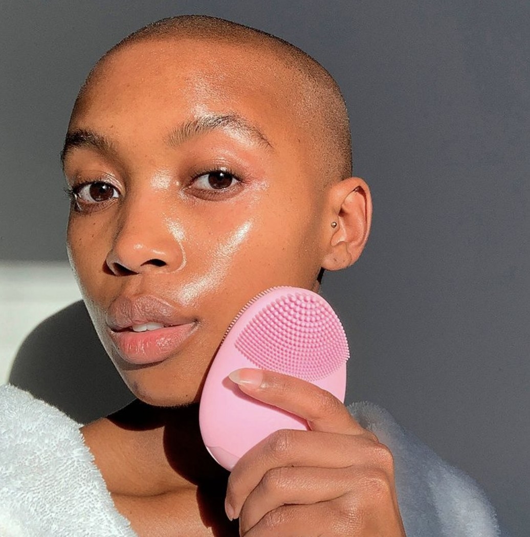 A model using a pink electric facial cleansing brush