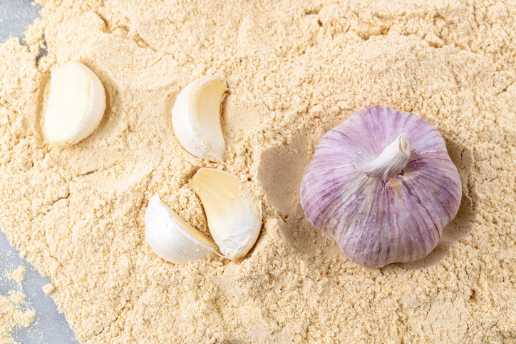 A bulb of garlic and cloves on a pile of garlic salt