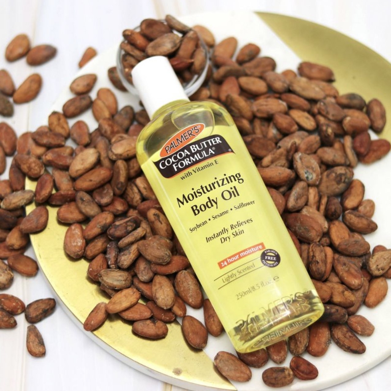 A bottle of body oil laid on top of beans in a plate