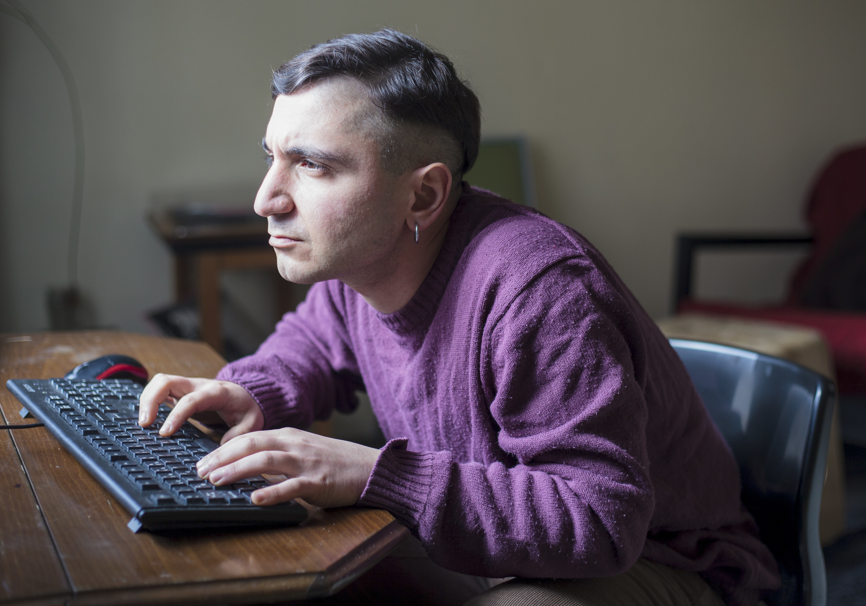 man hunching forward while using his computer