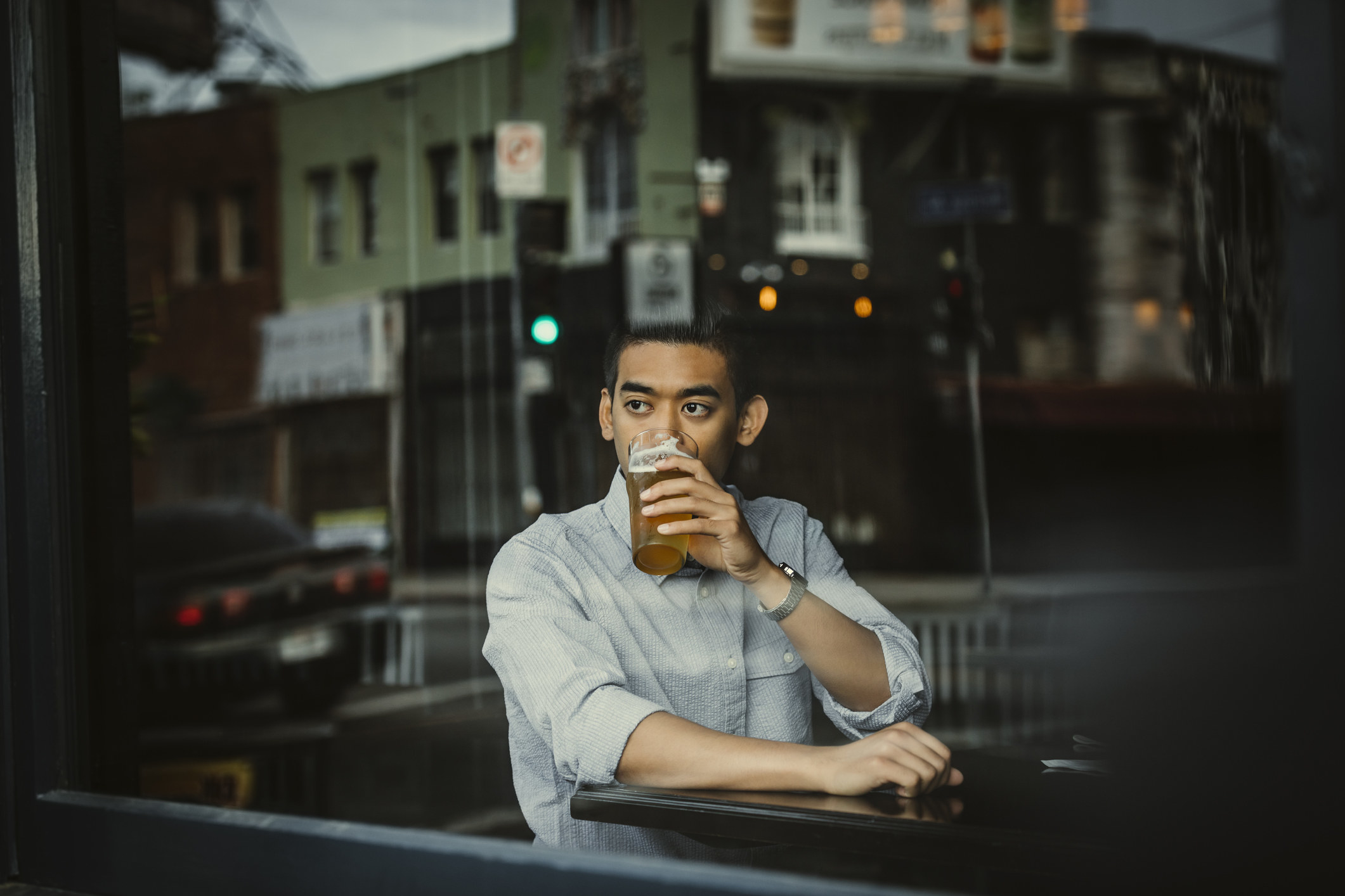 man drinking a beer and looking out the window