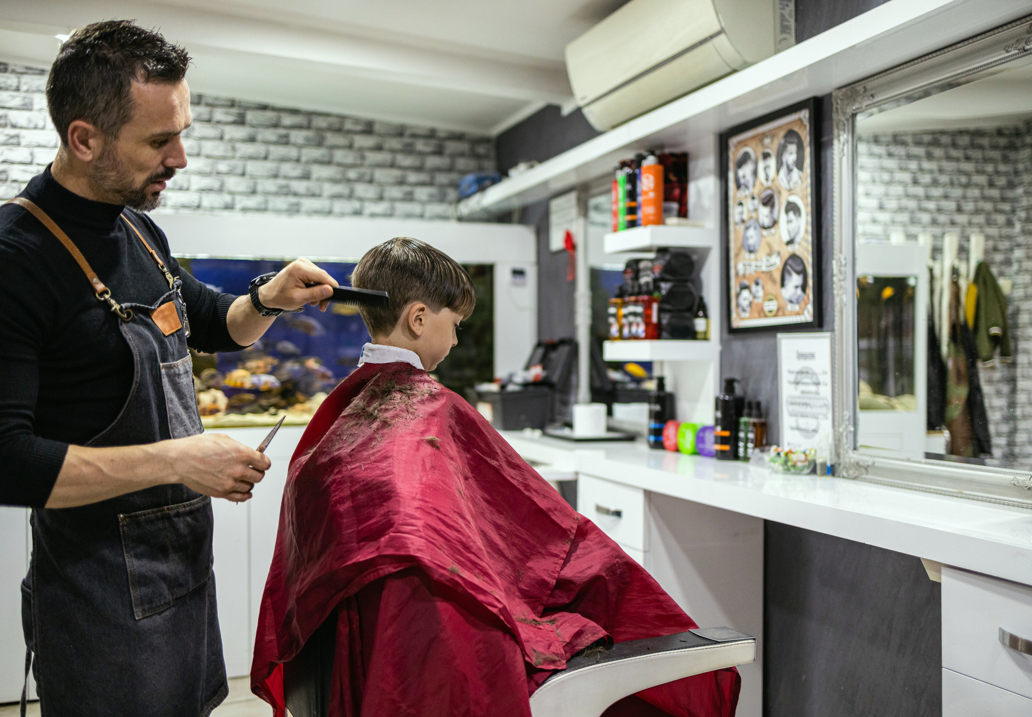 A barber cutting a young boy&#x27;s hair