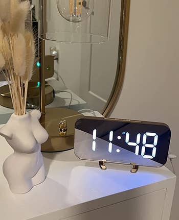 the gold alarm clock displayed on a reviewer's nightstand