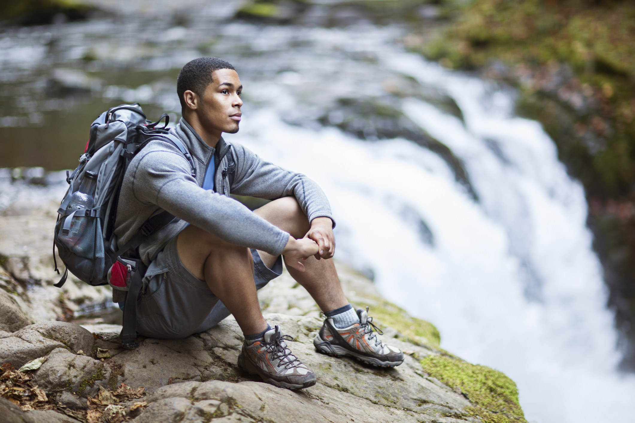backpacker sitting on the edge of a waterfall
