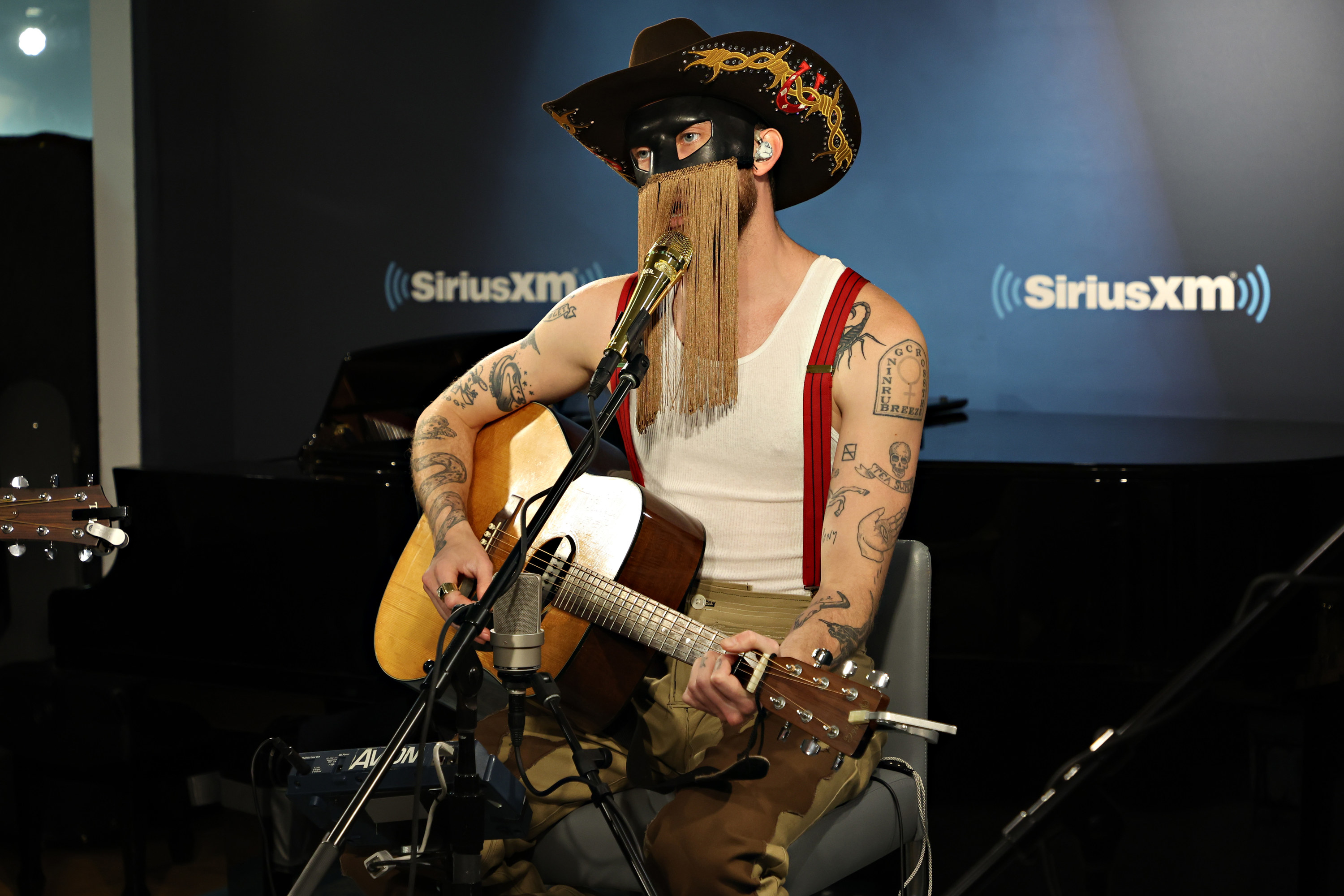 Orville singing into a microphone and playing a guitar in the SiriusXM studios