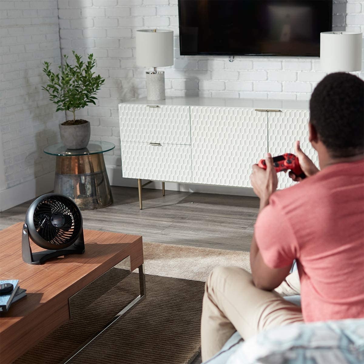 The fan on coffee table next to a person playing video games