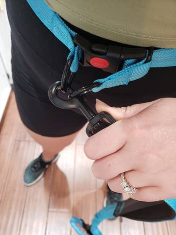 a reviewer showing how the leash attaches with two D rings and goes around your waist