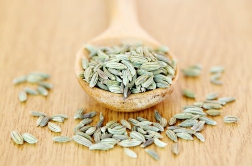 Fennel seeds in a bowl and on a wooden surface