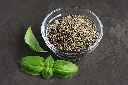 Fresh basil next to a small bowl of dried basil