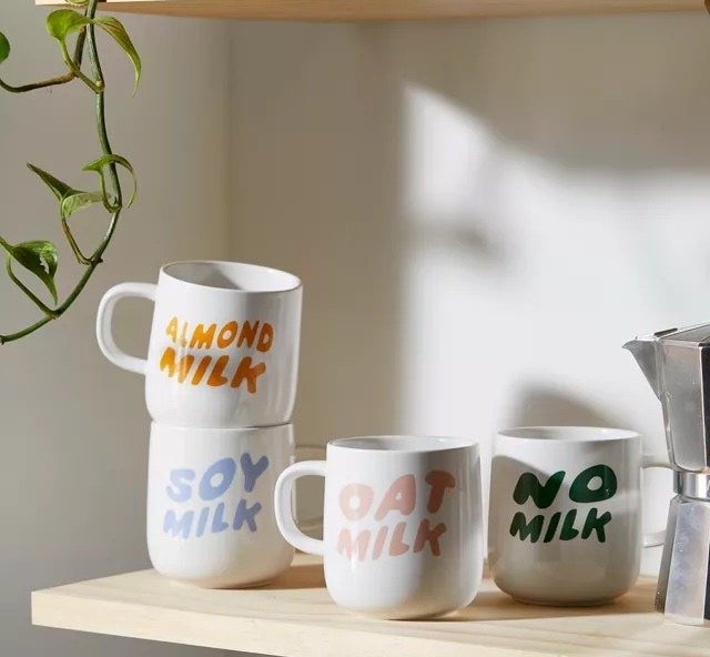 the set of mugs on a shelf in a kitchen next to an espresso pot