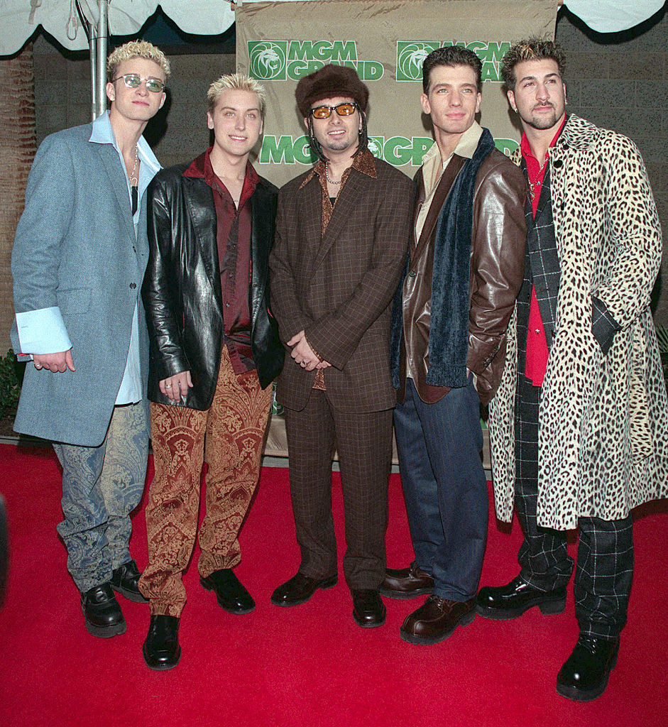 The members of NYSNC in colorful outfits ranging from asuits and leather jackets to paisley pants and a leopard-print coat