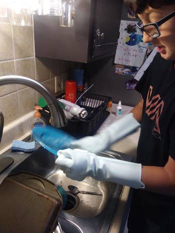 A customer review photo of a person using the gloves to wash a plate