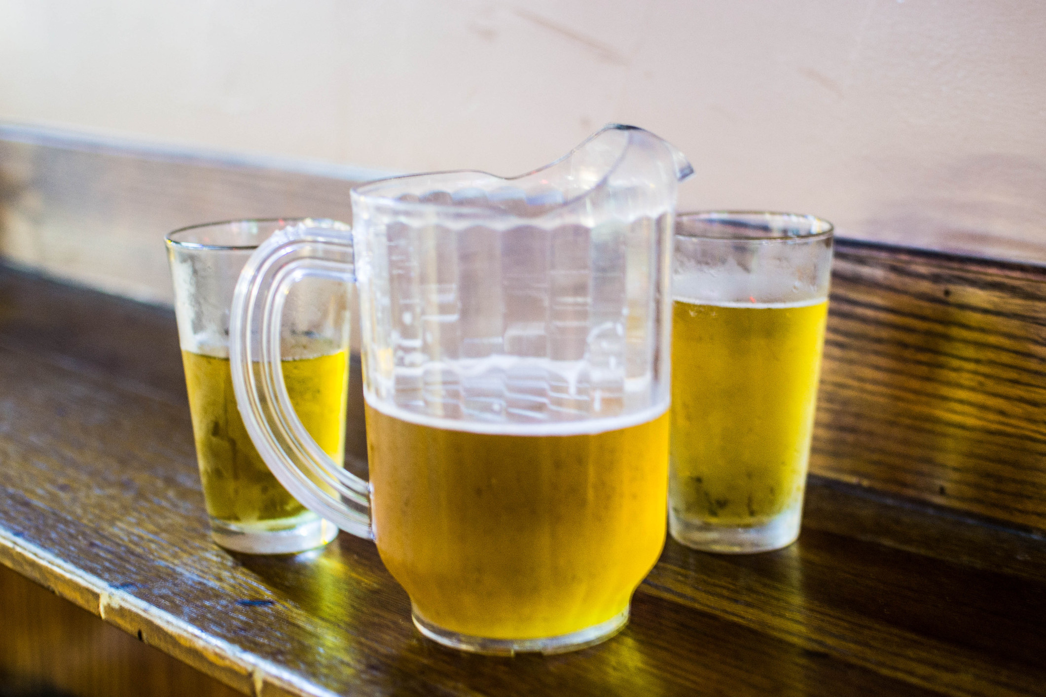 A beer pitcher next to two glasses