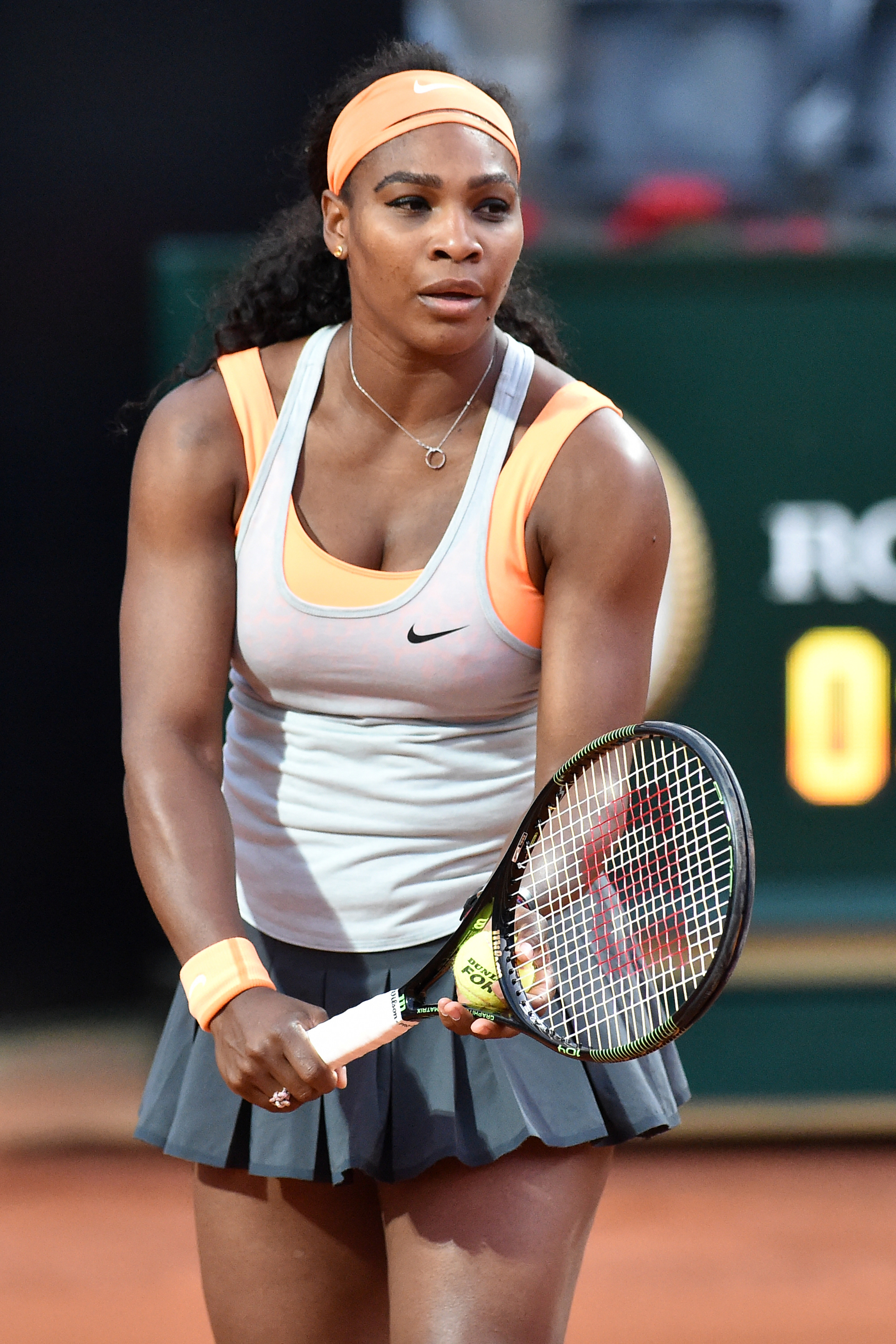 Serena Williams on the tennis court, holding a racquet and a ball.