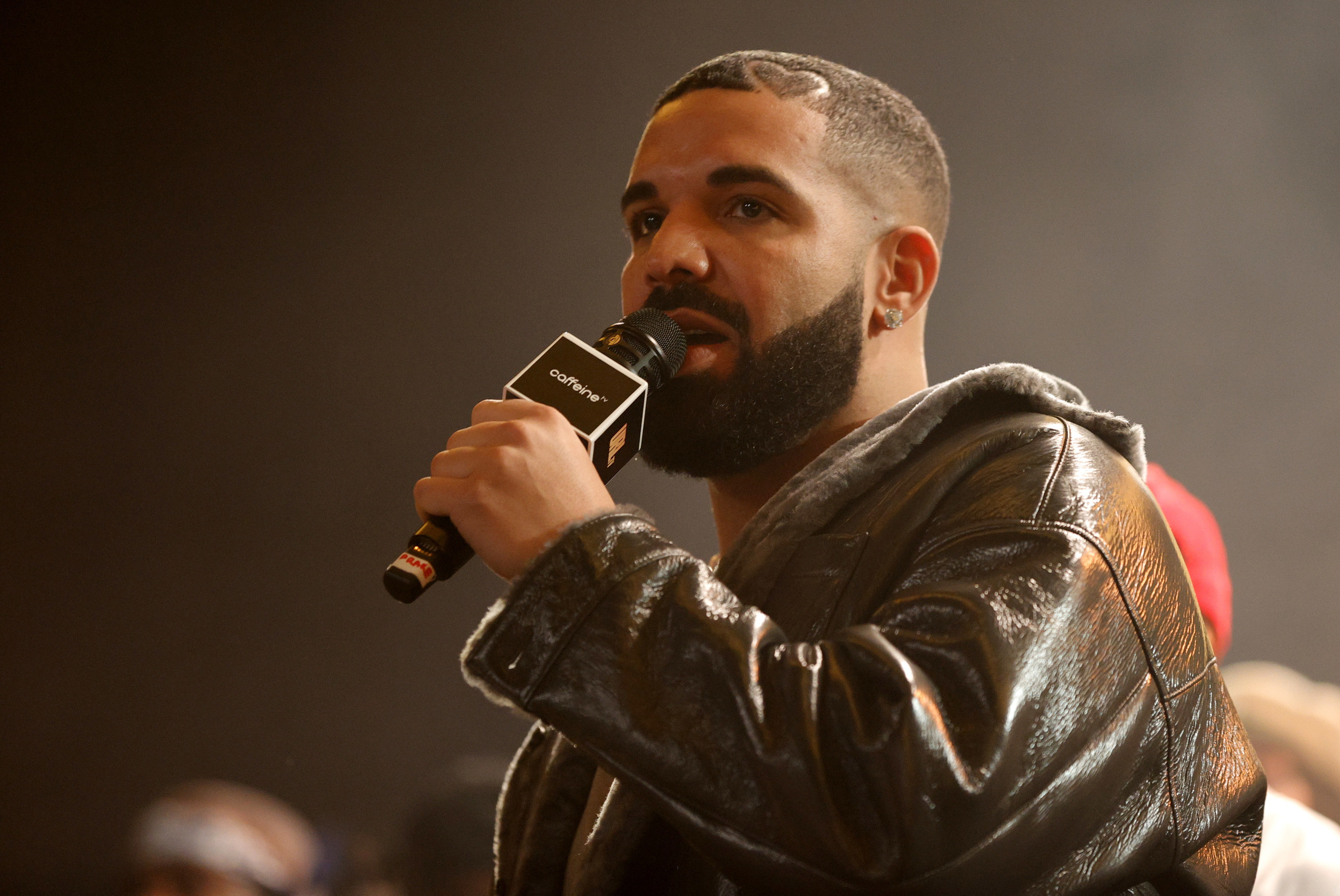 Drake holding a microphone and wearing a leather jacket.