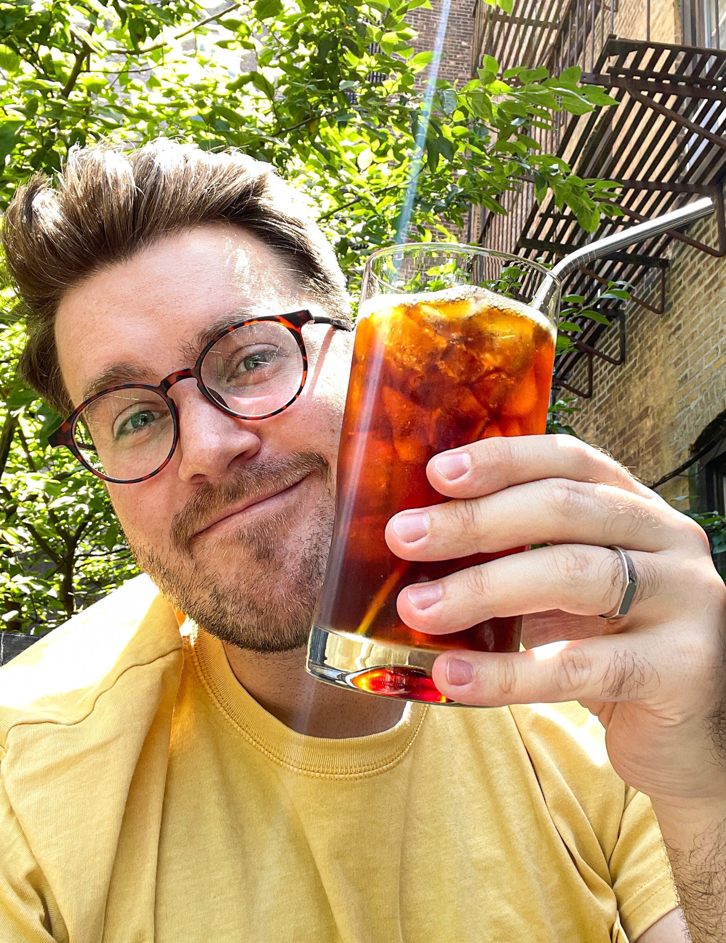 author holding up a glass of iced coffee outside