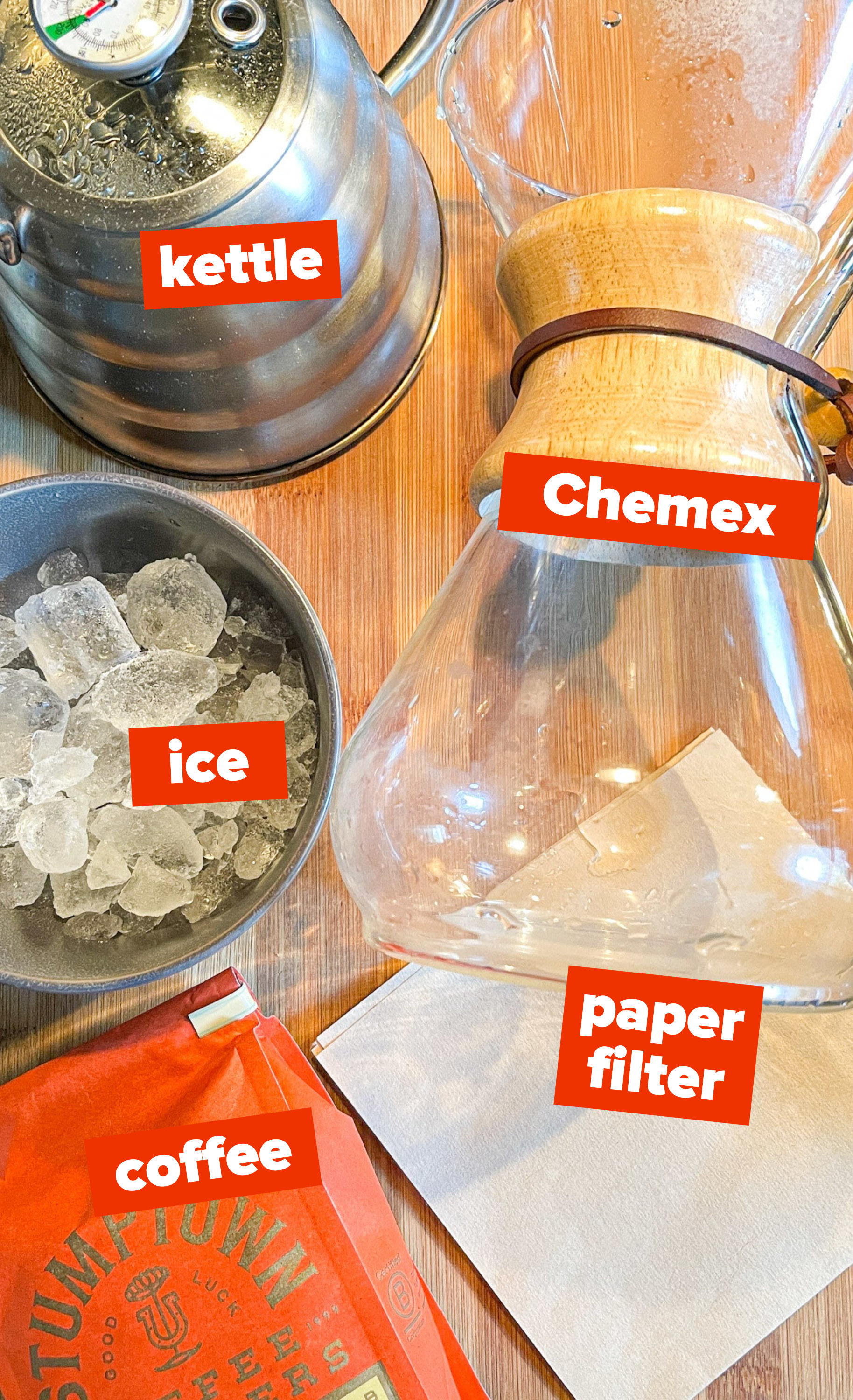 Ingredients for Japanese iced coffee laid on a cutting board: kettle, Chemex, ice, paper filter, coffee