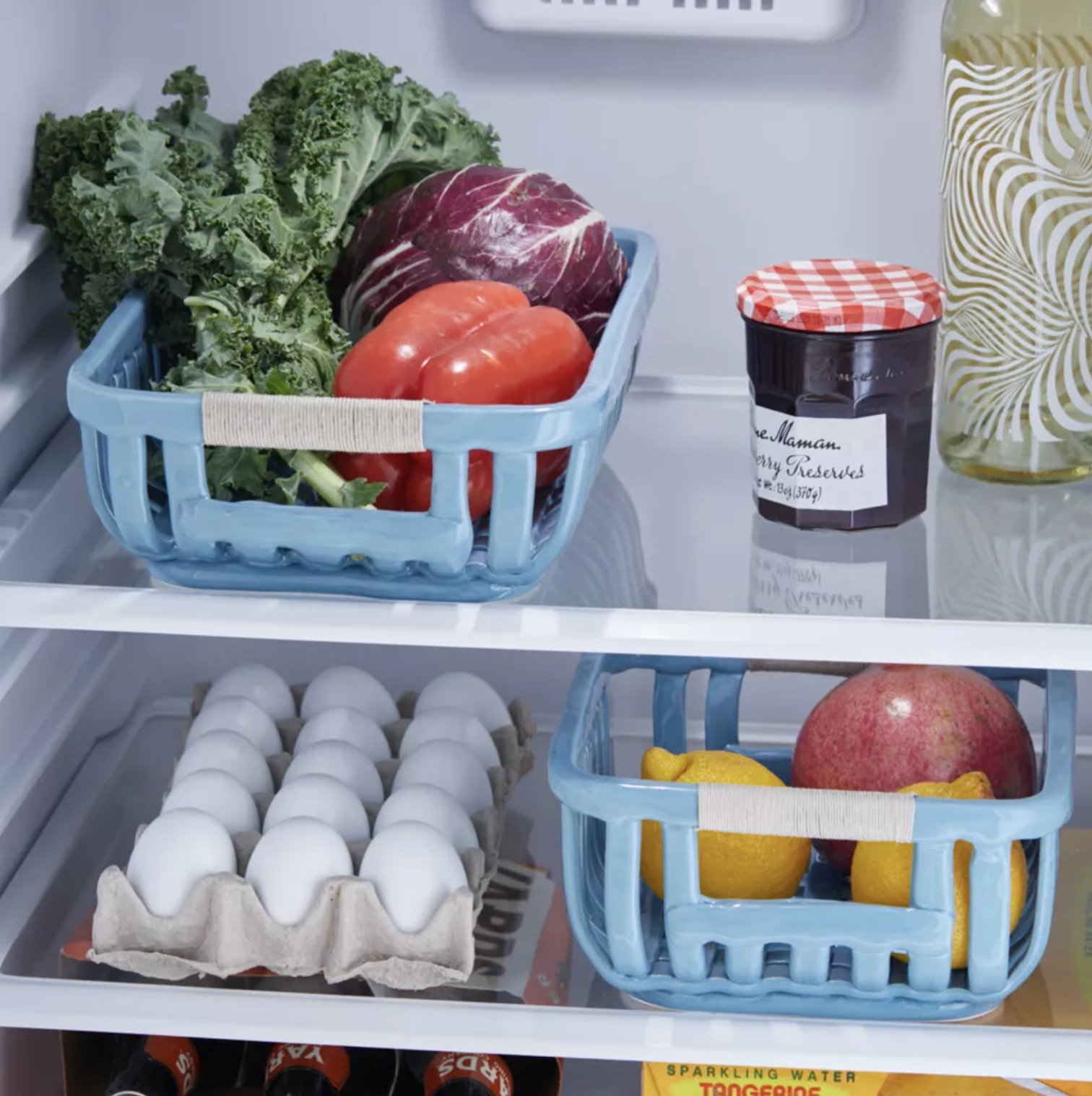 The baskets in a fridge with produce in them