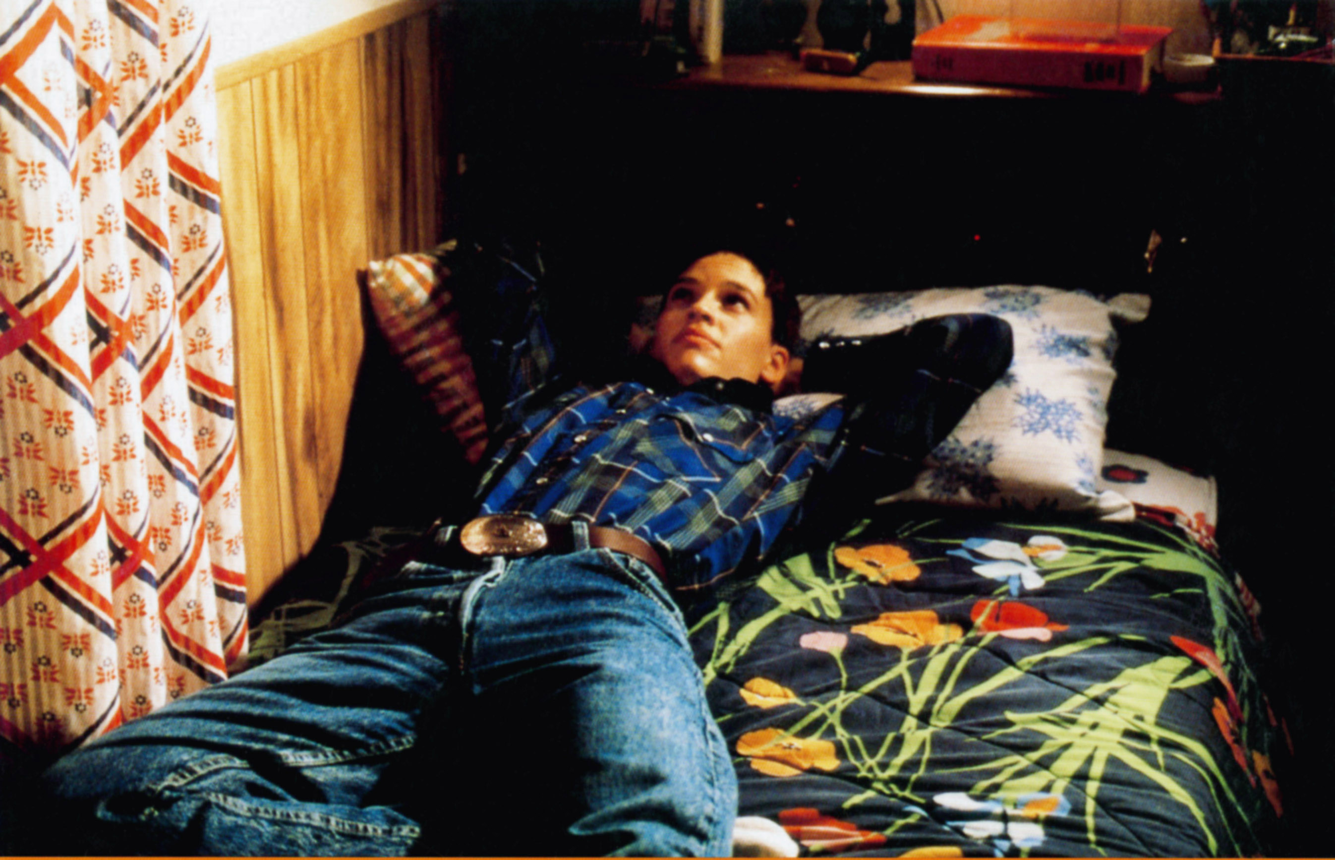 Hilary Swank as Brandon Teena sitting on a bed
