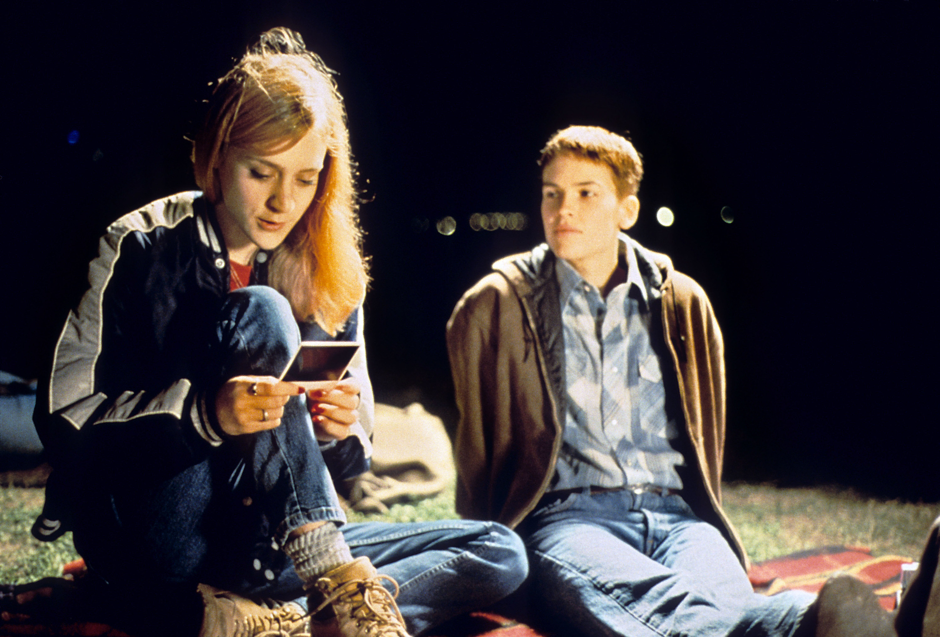 Hilary Swank sitting next to a teenage girl on the grass