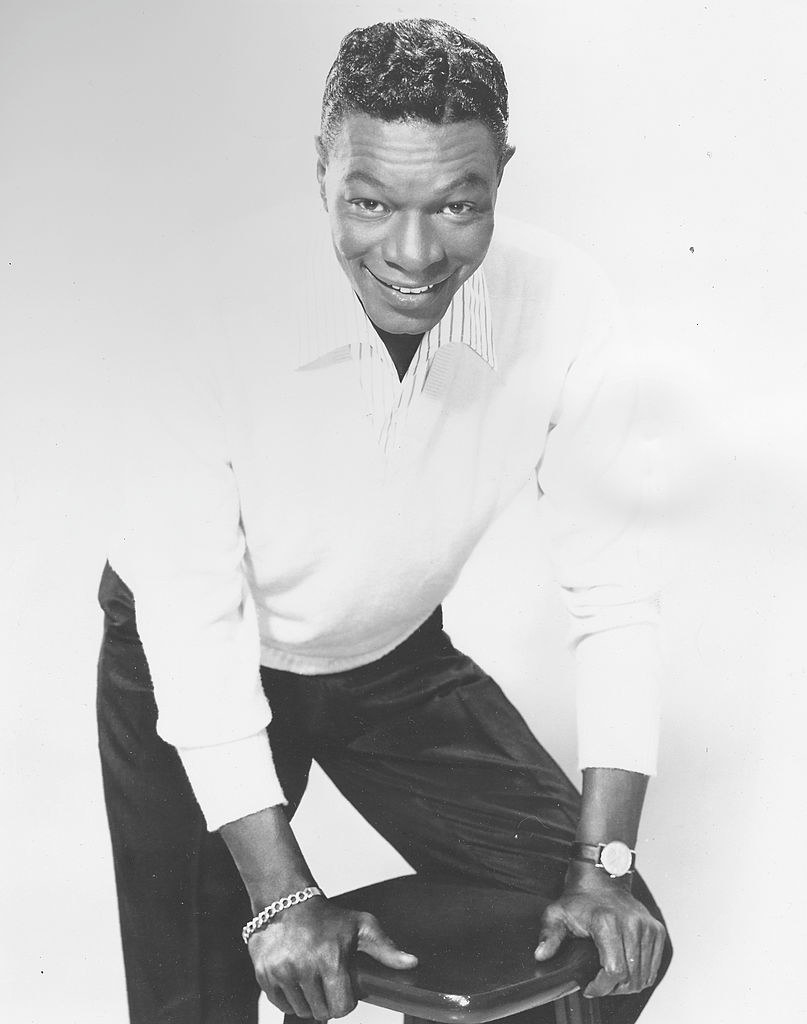 Cole posing for a portrait in 1953, resting on a stool