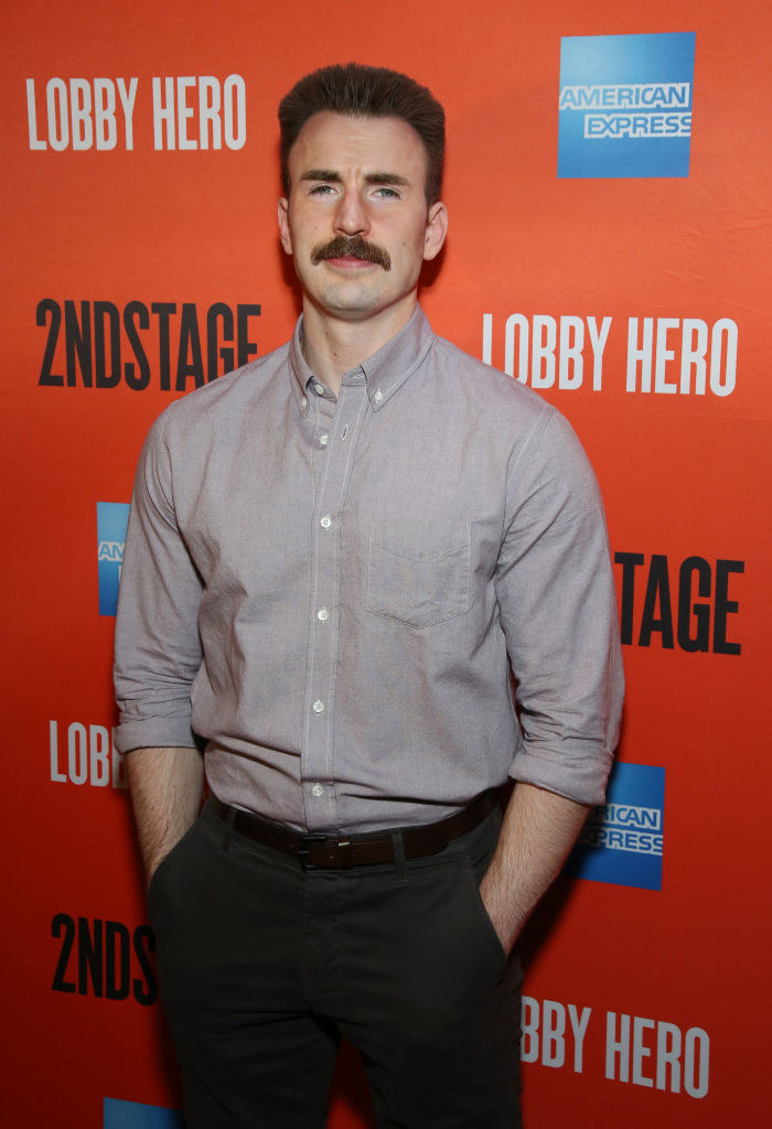 Chris Evans with his hands in his pockets with a mustache