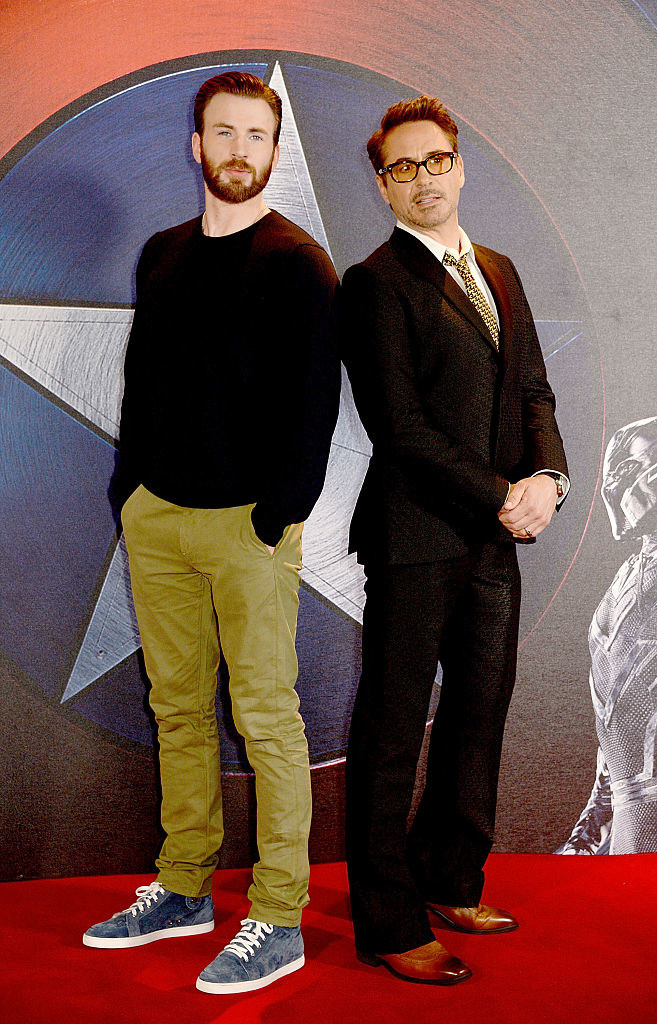 Chris Evans with his hands in his pockets standing back to back with Robert Downey Jr