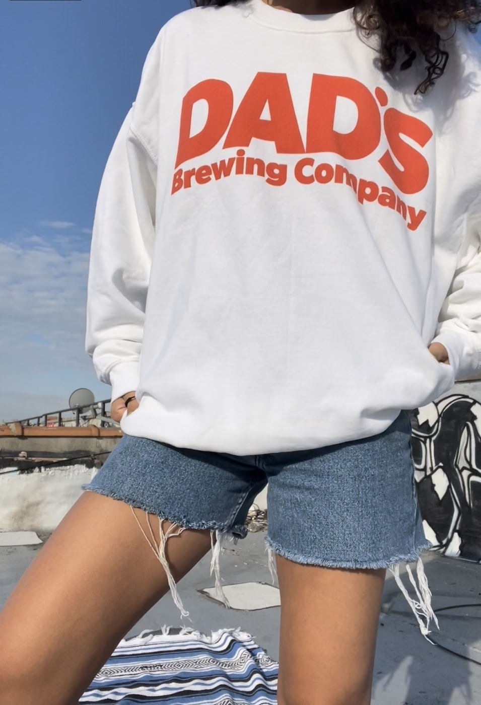 person in a white sweatshirt wearing &quot;dad&#x27;s brewing company&quot; in large orange letters