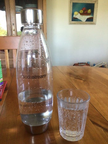 Sodastream bottle next to a glass filled with sparkling water