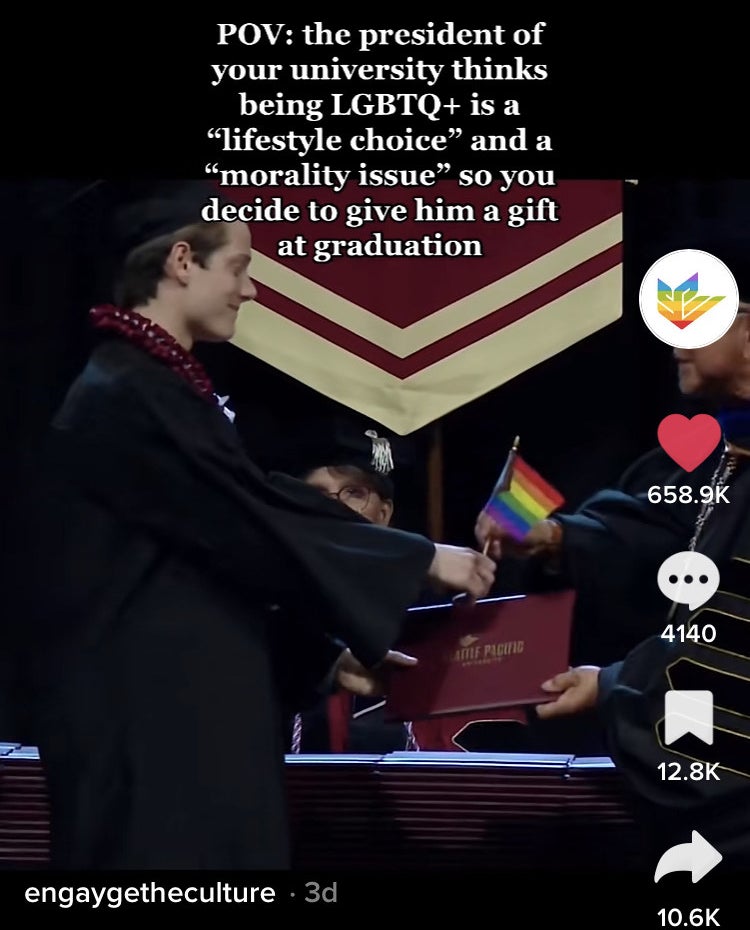 A third student with a pride flag at graduation