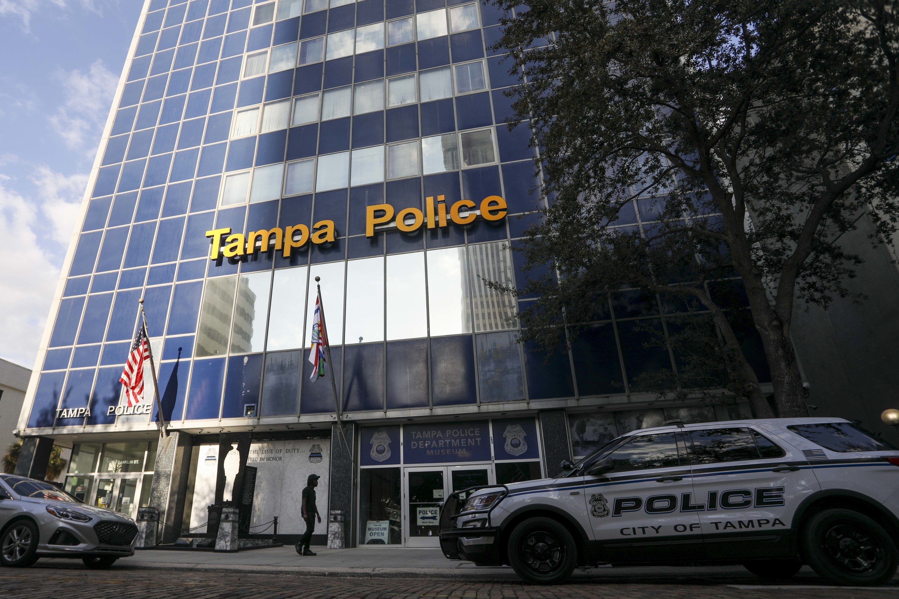 The exterior of a skyscraper reads &quot;Tampa Police&quot; with police vehicles parked on the street