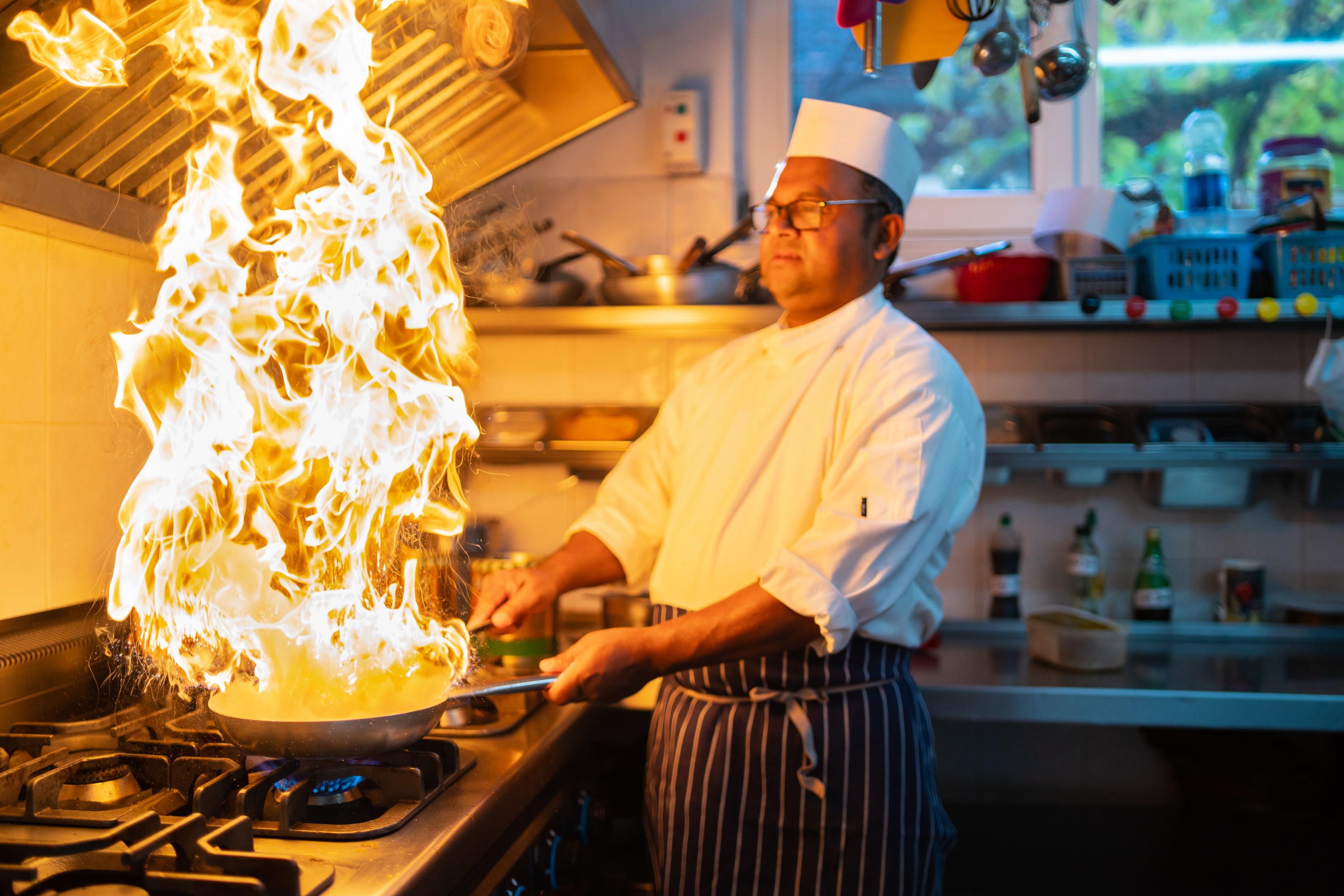 a chef with a frying pan playing with fire in the kitchen