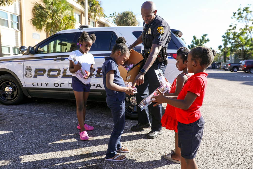 A black police officer interacts with several children outside in Tampa