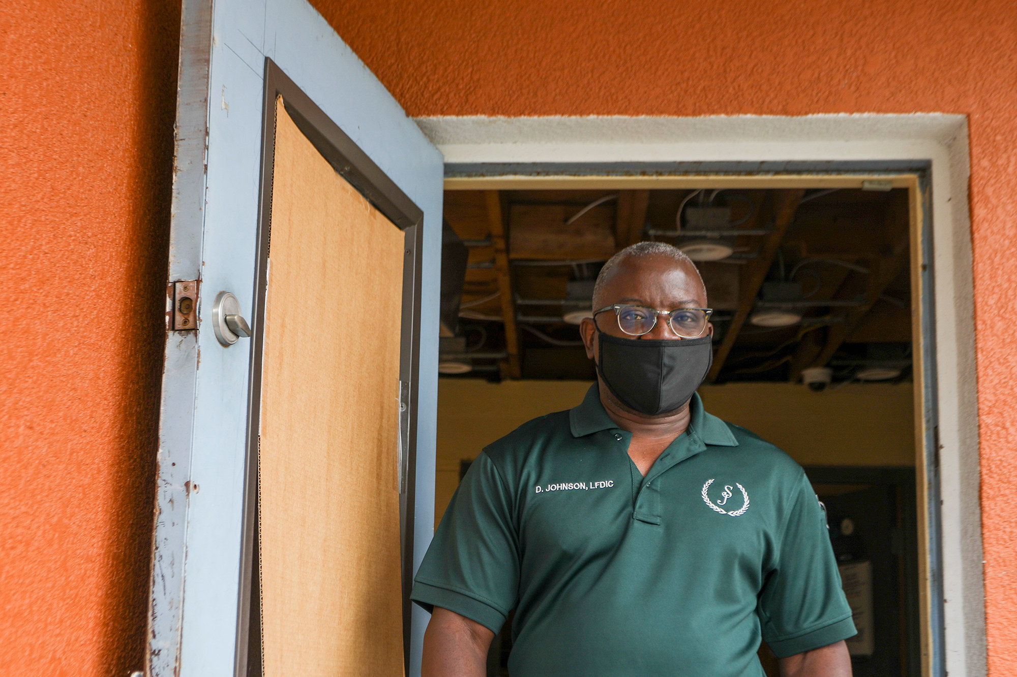 Darrell Johnson, wearing a face mask, stands in a doorway