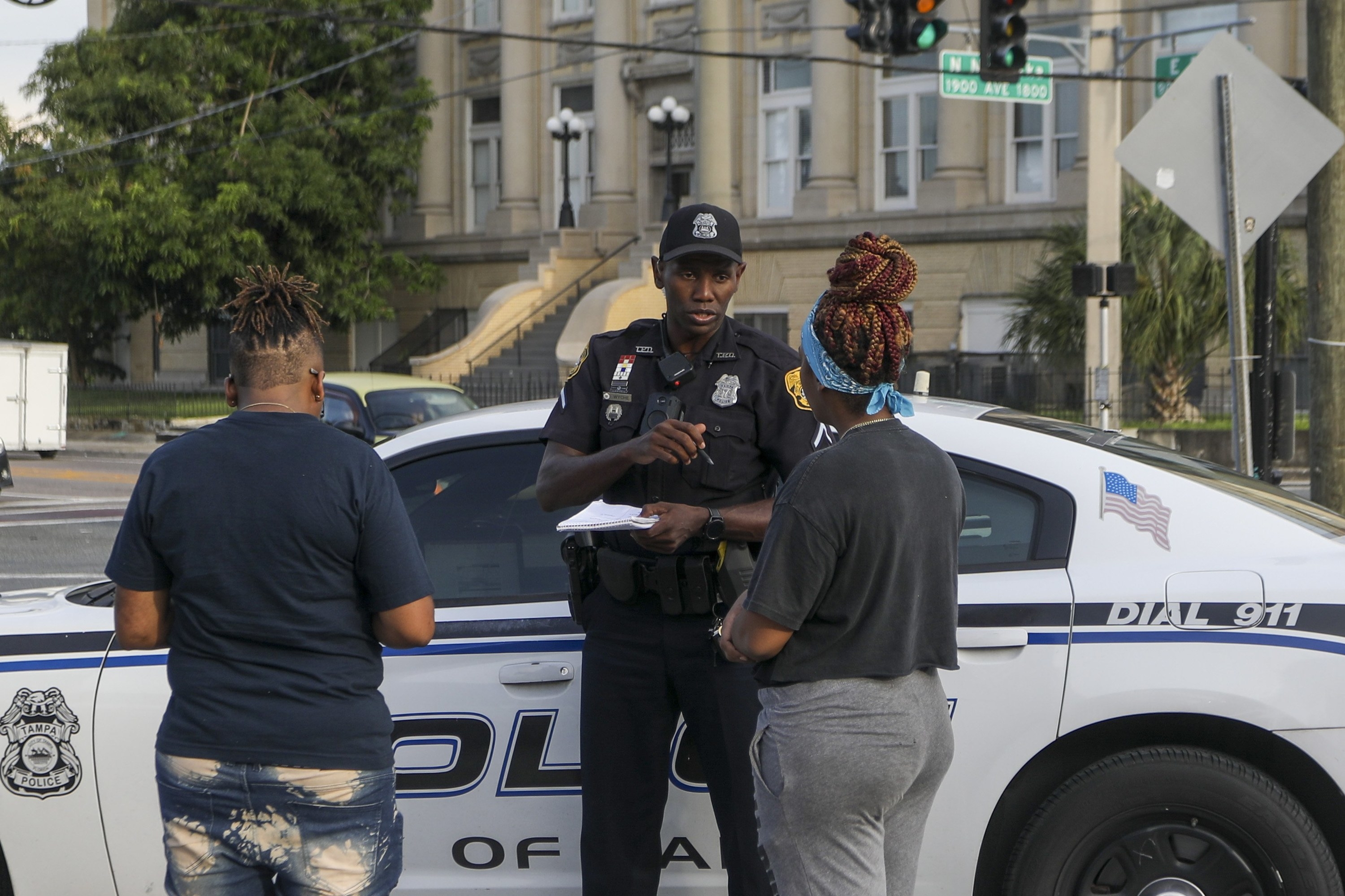 Officer Jerry Wyche speaks with people who got into a minor car accident, standing by a police vehicle