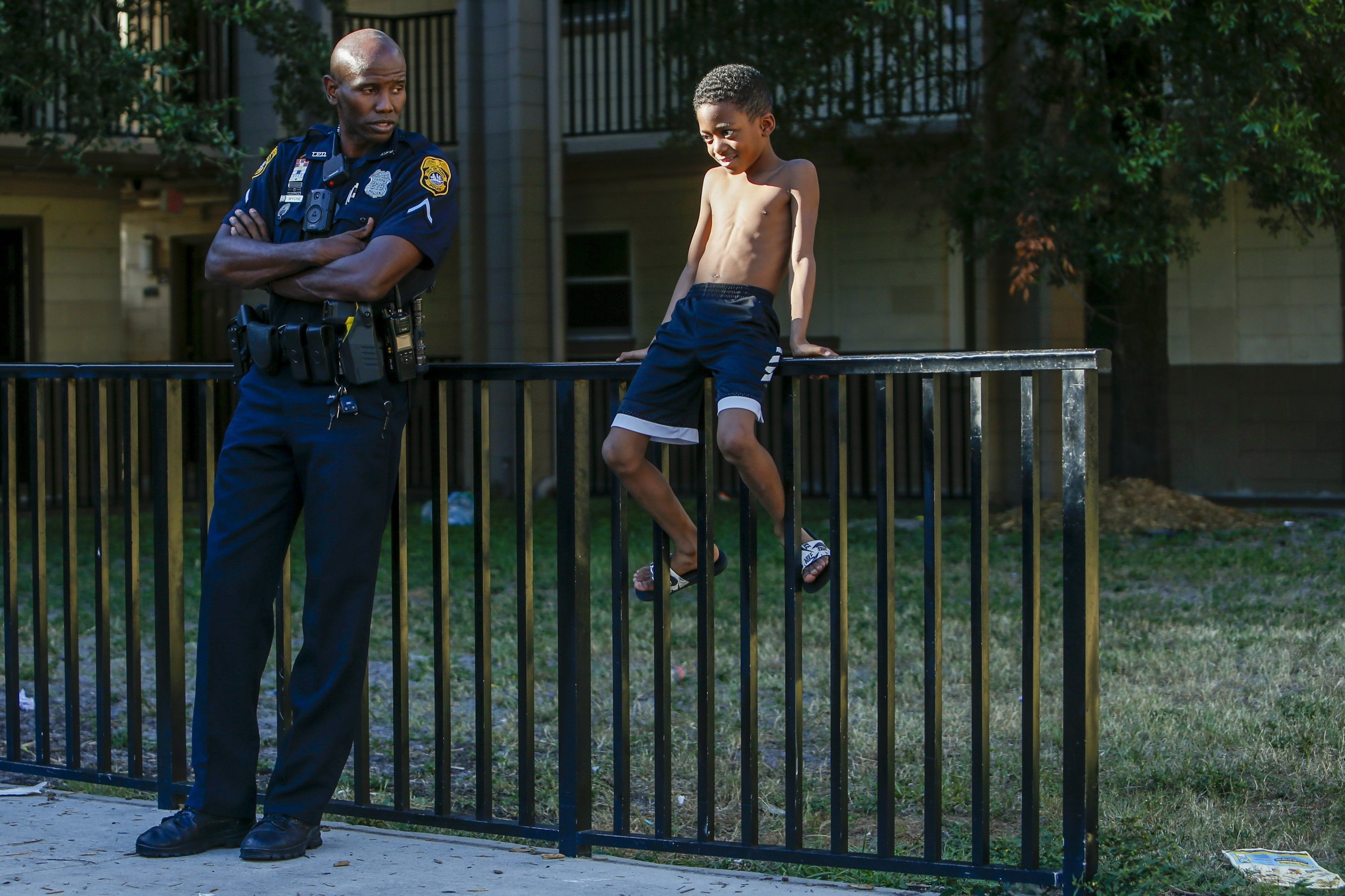 An image of Officer Jerry Wyche speaking with a young boy sitting on a fence outside