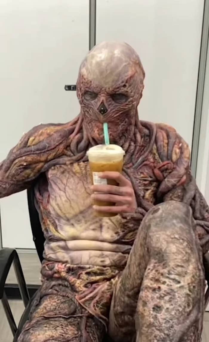 a person in a monster-like skeleton costume drinking Starbucks