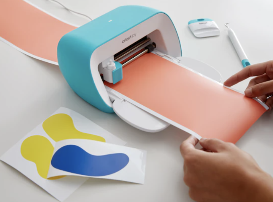 A person pulling a sheet through the Cricut machine